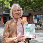 foto av forskaren Marianne Törner som visar sin bok Hälsobringande sjukvård - för personal och patienter